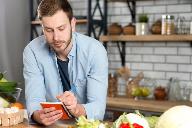 portrait-man-writing-recipe-his-diary-kitchen_23-2148075959